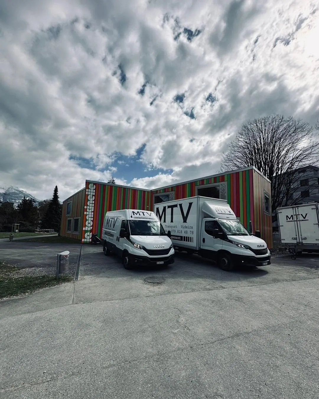 Trois véhicules MTV stationnés devant un bâtiment coloré en Valais