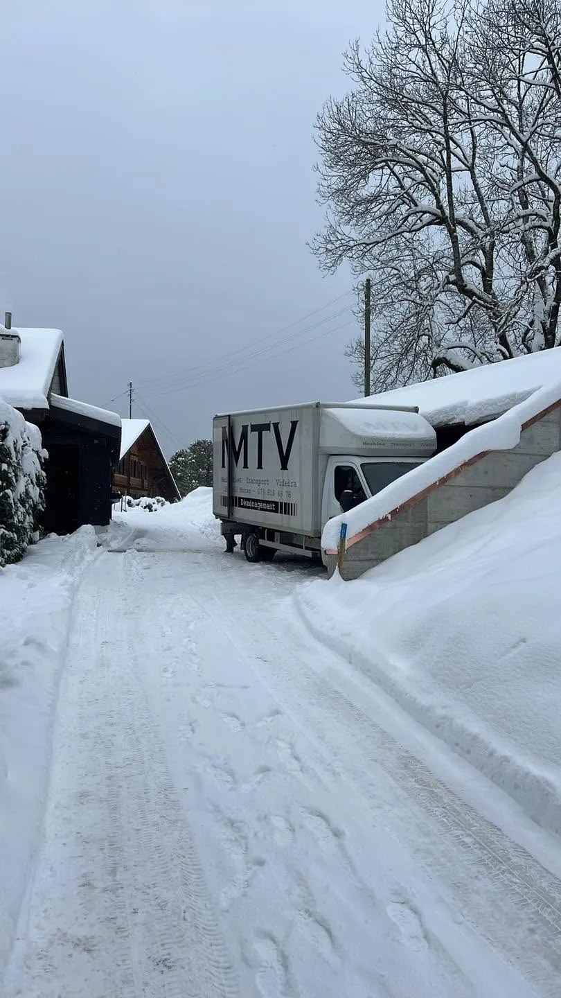 Camion MTV dans la neige profonde entre des chalets de montagne en Valais